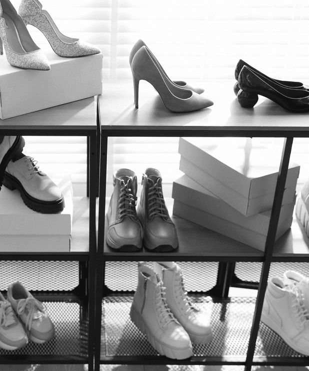 Estantería de tienda con zapatos de tacón, botas y zapatillas junto a cajas de calzado